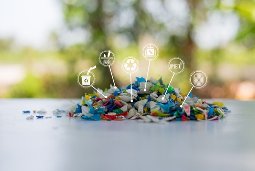 Plastic bottles crushed into small pieces, ready for recycling, showing the process of plastic waste management.